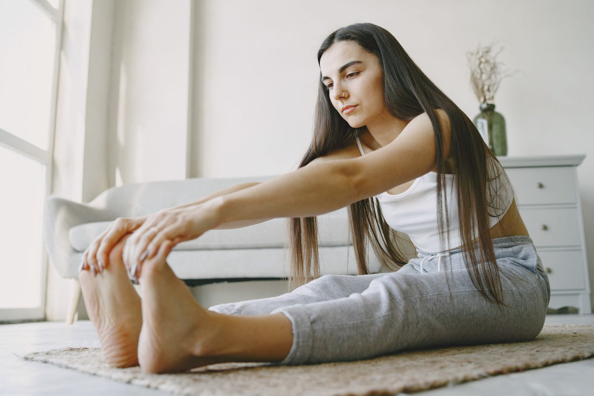 Young woman stretching on a rug in a light-filled room